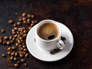 white espresso coffee Cup and roasted beans on old rusty brown background. copy space