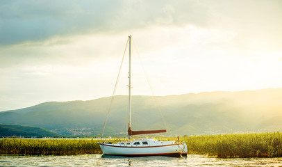 North macedonia. Ohrid. White sailboat on Ohrid lake beside reeds in sunset. Horizontal photo