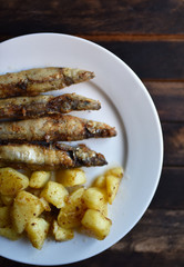 fried fish with potatoes on a wooden table top view