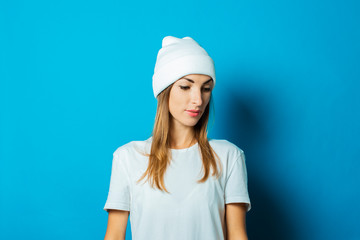 Young woman in white hat and t-shirt on a blue background