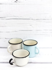 Enameled mugs in retro style on an old wooden background.