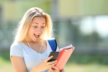 Obraz premium Surprised student checking phone messages in a campus