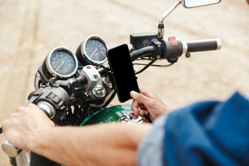 Close up of a man holding handle bars and using mobile phone