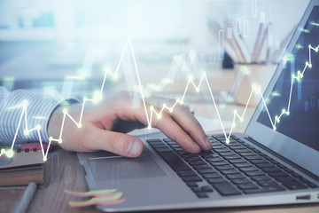 Double exposure of stock market graph with man working on laptop on background. Concept of financial analysis.