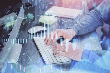 Stock graph with businessman typing on computer in office on background. Concept of analysis. Double exposure.