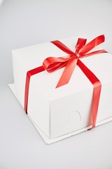 Closeup of cakes in white boxes tied with a red ribbon