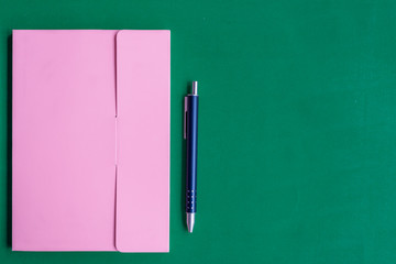 The notebook and pen is on green paper background