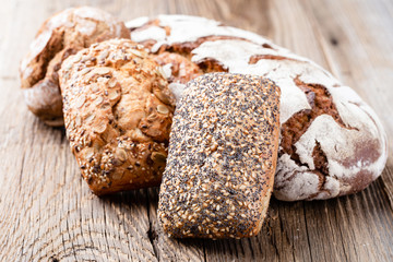 Gold rustic crusty loaves of bread and buns on wooden background. Still life captured from above top view, flat lay.