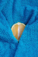 Sliced lemon with turquoise towel. Partially covered. The photograph depicts a woman's genital area.
