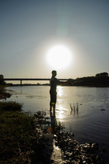 Silhouette of a fisherman at sunset on the background of the sea and sky