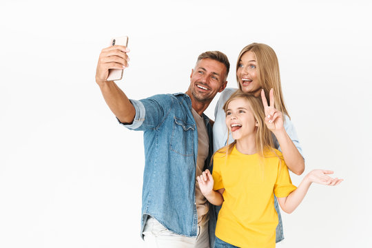 Photo of happy woman and man with little girl smiling while taking selfie on cellphone
