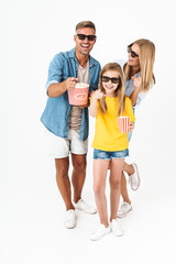 Photo of happy family in 3D glasses holding popcorn bucket while watching movie in cinema