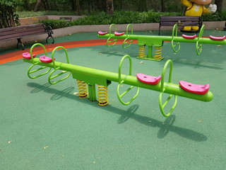 Green seesaws with pink seats in a playground