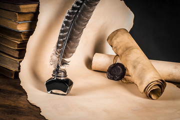 Fountain pen with inkwell on the background of scrolls of papyrus and books