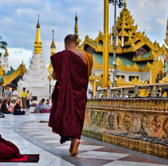 buddhist pilgrims dressed in red traditional robes praying in the golden temple in myanmar