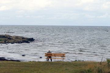 einsame Frau auf Bank am Meer