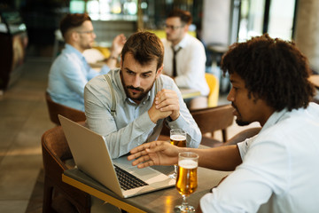 Men are sitting at table in modern cafe. Talk about work