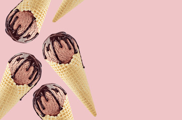 Decorative border of chocolate ice cream in crisp waffle cones with sweet brown sauce on pink...