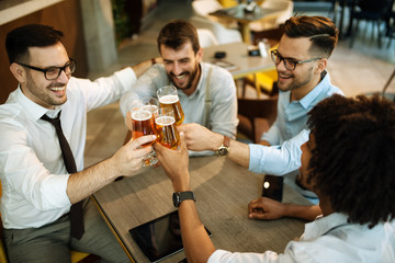 Handsome businessmen are drinking beer, talking and smiling while resting at the pub