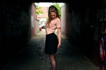 Low key city portrait of an elegant young woman dancing in a dark alley near the city centre