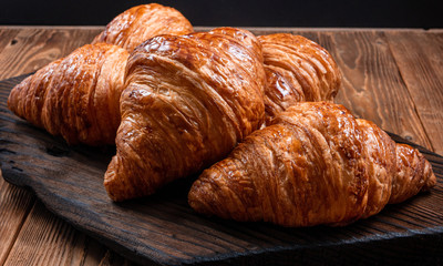 Fresh fragrant crispy french croissants on a wooden board. Delicious pastries for a refined breakfast