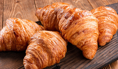 Fresh fragrant crispy french croissants on a wooden board. Delicious pastries for a refined breakfast