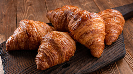 Fresh fragrant crispy french croissants on a wooden board. Delicious pastries for a refined breakfast