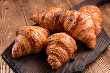 Fresh fragrant crispy french croissants on a wooden board. Delicious pastries for a refined breakfast