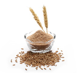Spelt bran and grains with wheat ears in glass bowl isolated on white background