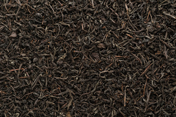 Dry black tea leaves as a background, shot from above.