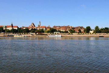 Obraz premium Summer view of the Old Town - historic quarter of Warsaw with Royal Castle and red roof tenements seen from the Vistula river side. Warsaw, Poland