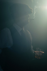 Retro businessman with cap smokes cigarette in smoky room.