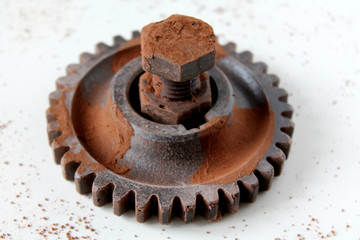 Rusty bolt, nut and gear wheel made of chocolate isolated on white background. Chocolate chip scattered on smooth surface. Mechanic gearing background. Father's day card obects