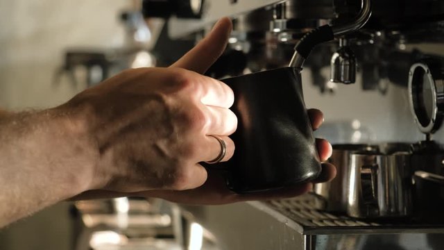 Close-up of Barista hand steaming milk for coffee.