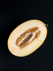 half of the ripe amal melon with seeds on a black background
