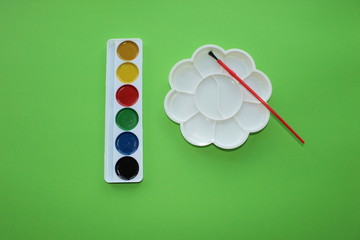 paint, palette to mix on a green background. Watercolor and colored objects for school and...
