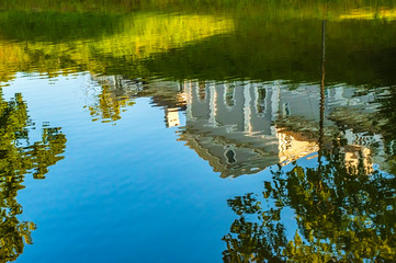 Reflection of a building in the style of Russian classicism in the pond of the park