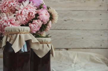 Jars of jam and a bouquet of pink flowers