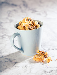 Chocolate chip cookies in blue cup on marble stone background. Selective focus. Copy space. Toned.