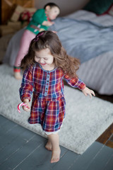 Cute little girl in Christmas red dress, eat candy cane