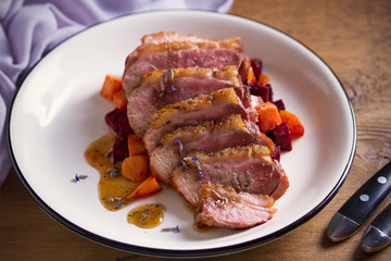Sliced duck breast fillet with sweet potatoes and  beetroot on plate