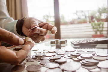 Cropped Image Of Businessman counting coins Using Calculator at Desk In Office. Businessperson Hand...