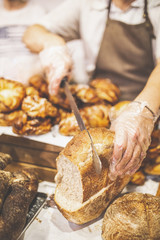Close up of baker cutting whole grain bread.