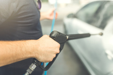 Close up of manual car wash with pressurized water in car wash.