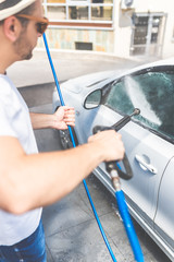 Close up of manual car wash with pressurized water spray in car wash.