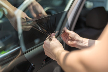 Close up of worker pulling off sun protection tinted foil from side car window.