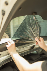 Close up shot hands of man removing old car window film