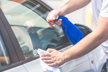 Man hands cleaning and spaying car exterior.