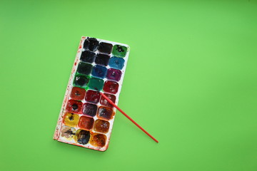 paint on a green background. Watercolor and colored objects for school and creativity.