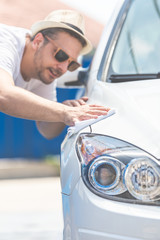 Modern young man cleaning car with cloth, car maintenance concept.